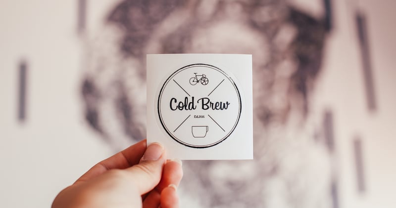 Crop person showing sticker of cafe with inscription