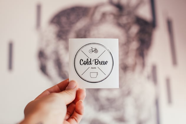 Crop person showing sticker of cafe with inscription
