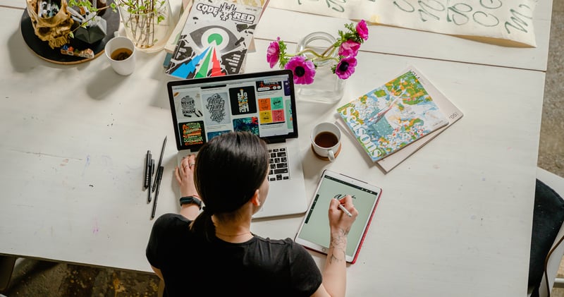 Photo of Woman Writing on Tablet Computer While Using Laptop
